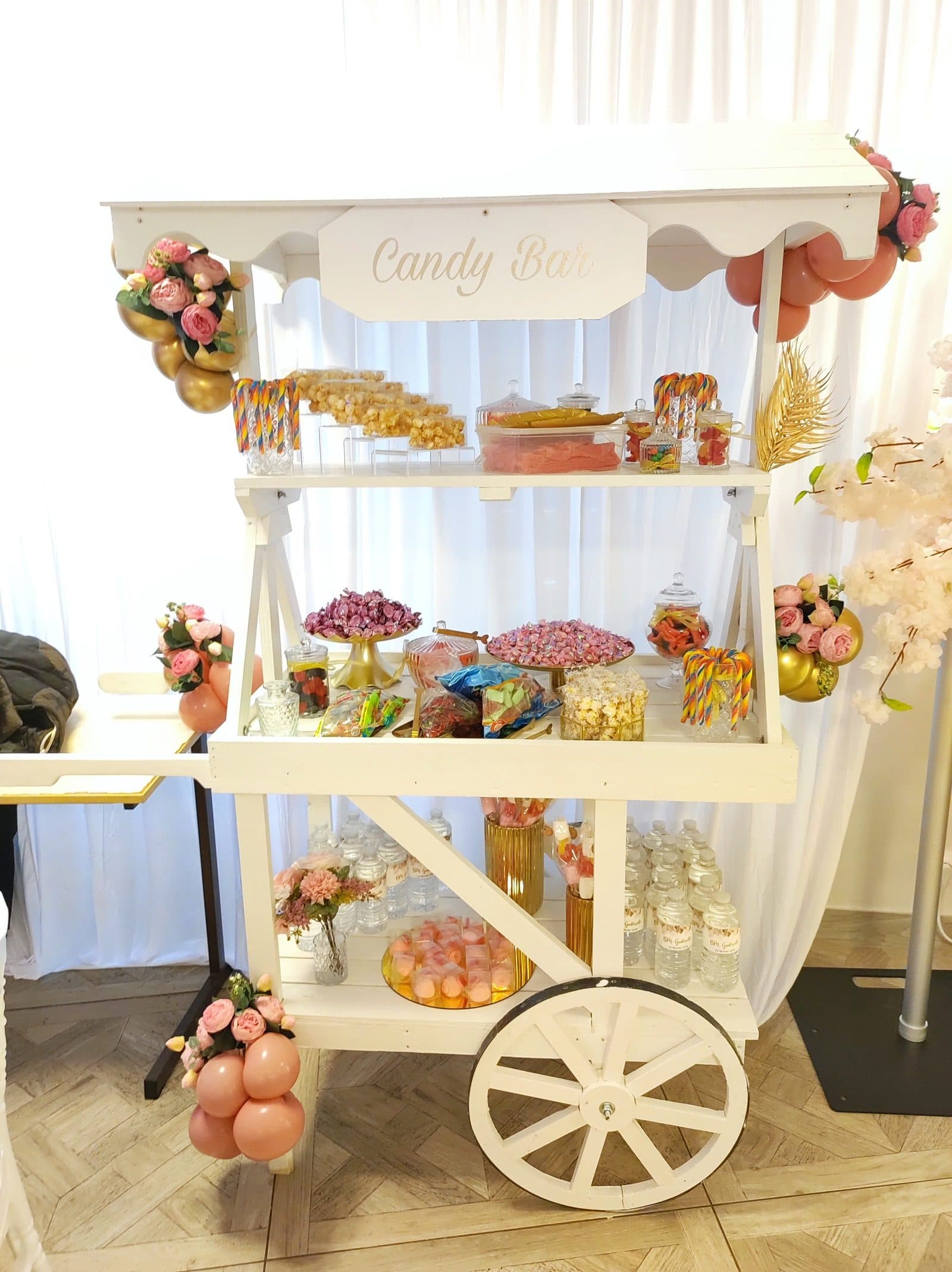 Chariot candy bar blanc avec ballons et présentoirs gourmands